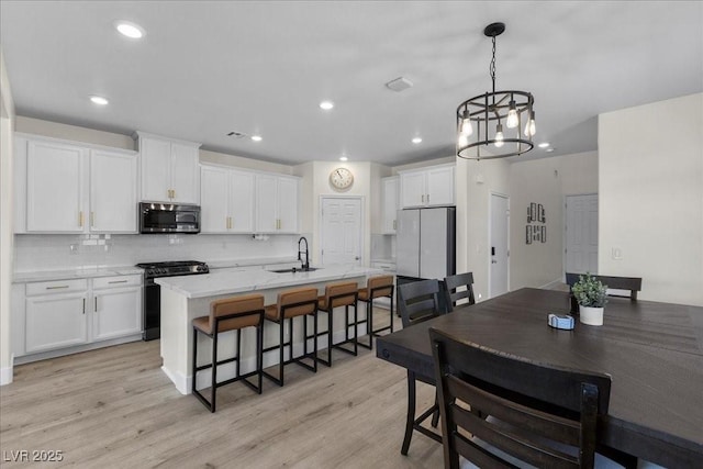 4030 Midnight Crest Ave, North Las Vegas, NV 89031 - kitchen with stainless steel microwave, black gas range oven, a sink, white cabinetry, and a breakfast bar
