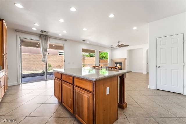 512 Los Dolces St, Las Vegas, NV 89138 - kitchen with a kitchen island, ceiling fan, brown cabinetry, light tile patterned floors, and a glass covered fireplace