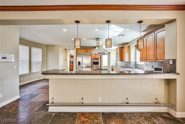 1737 Cypress Manor Dr, Henderson, NV 89012 - kitchen with stainless steel appliances, island exhaust hood, baseboards, brown cabinetry, and dark stone finish flooring