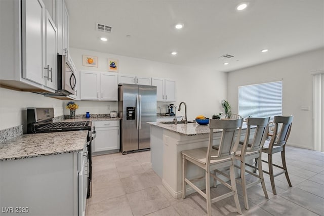 392 Canary Song Dr, Henderson, NV 89011 - kitchen featuring appliances with stainless steel finishes, a sink, a kitchen bar, light stone countertops, and recessed lighting