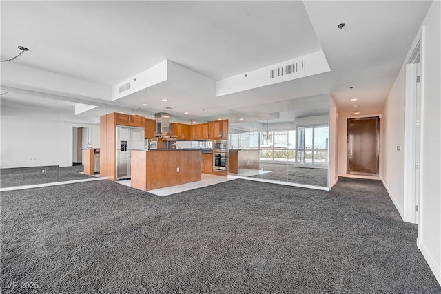 4525 Dean Martin Dr Unit 909, Las Vegas, NV 89103 - kitchen featuring open floor plan, built in appliances, wall chimney range hood, brown cabinets, and a kitchen island
