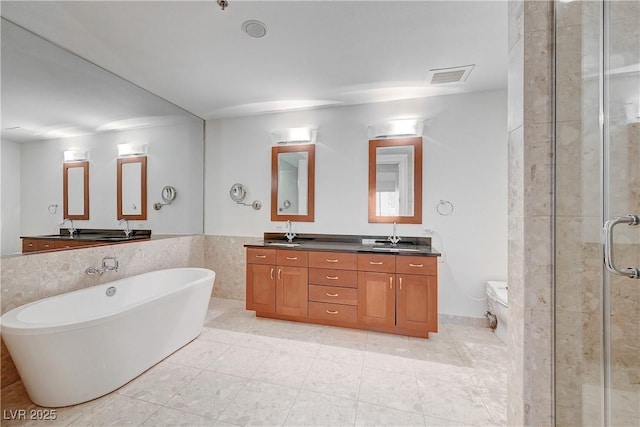 4525 Dean Martin Dr Unit 909, Las Vegas, NV 89103 - full bath with double vanity, a stall shower, a freestanding bath, tile walls, and a wainscoted wall