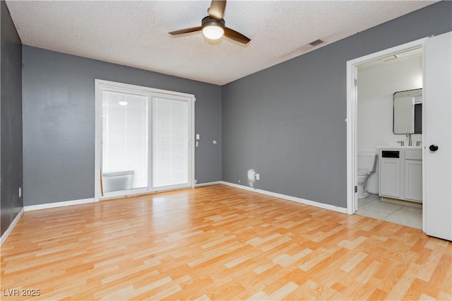 4205 Thicket Ave, North Las Vegas, NV 89031 - unfurnished bedroom with light wood-type flooring, a textured ceiling, baseboards, ensuite bathroom, and a ceiling fan