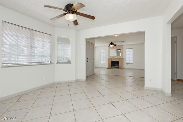 4205 Thicket Ave, North Las Vegas, NV 89031 - unfurnished living room featuring ceiling fan, light tile patterned floors, a brick fireplace, a textured ceiling, and baseboards