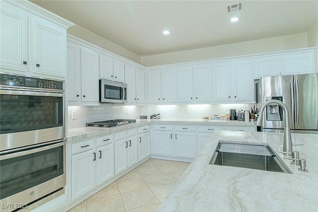 10744 Balsam Creek Ave, Las Vegas, NV 89144 - kitchen featuring stainless steel appliances, a sink, tasteful backsplash, light stone countertops, and white cabinets