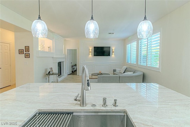 10744 Balsam Creek Ave, Las Vegas, NV 89144 - kitchen featuring a sink, a fireplace, hanging light fixtures, and light stone counters