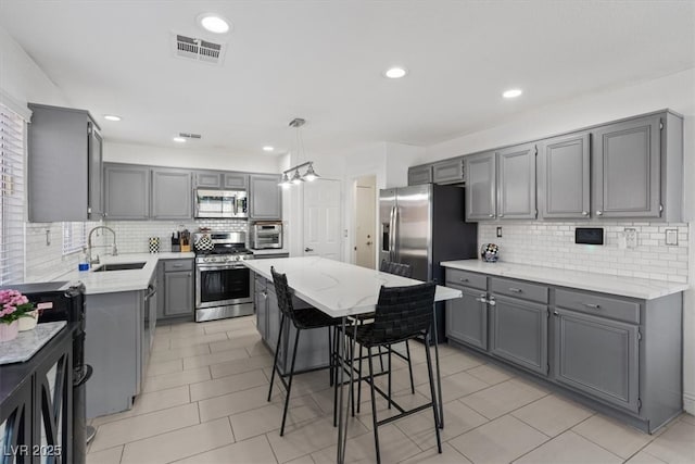 600 Beresford Ave, Las Vegas, NV 89123 - kitchen with stainless steel appliances, gray cabinets, a sink, decorative backsplash, and a kitchen island