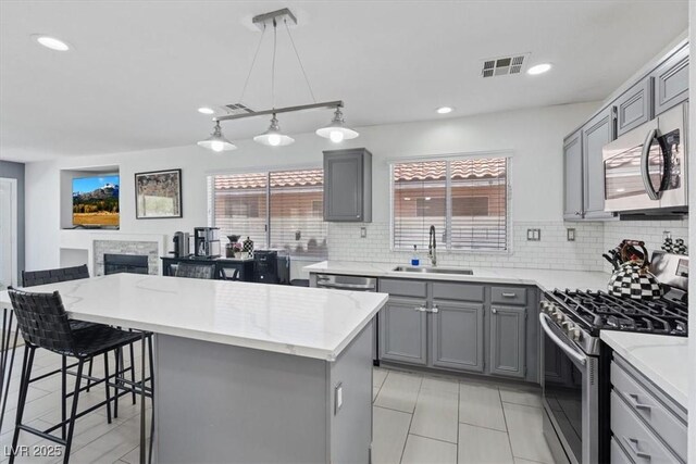 600 Beresford Ave, Las Vegas, NV 89123 - kitchen featuring appliances with stainless steel finishes, gray cabinetry, decorative backsplash, light stone counters, and a breakfast bar
