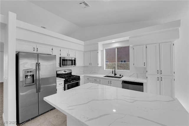 5437 Escallonia St, Las Vegas, NV 89149 - kitchen featuring stainless steel appliances, a sink, vaulted ceiling, white cabinetry, and light stone counters
