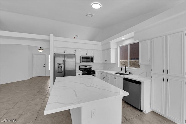 5437 Escallonia St, Las Vegas, NV 89149 - kitchen featuring appliances with stainless steel finishes, a sink, light tile patterned floors, vaulted ceiling, and a kitchen island