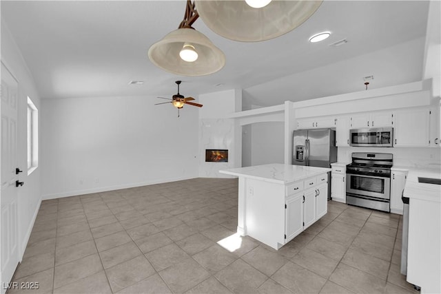 5437 Escallonia St, Las Vegas, NV 89149 - kitchen with stainless steel appliances, white cabinets, a ceiling fan, a kitchen island, and vaulted ceiling