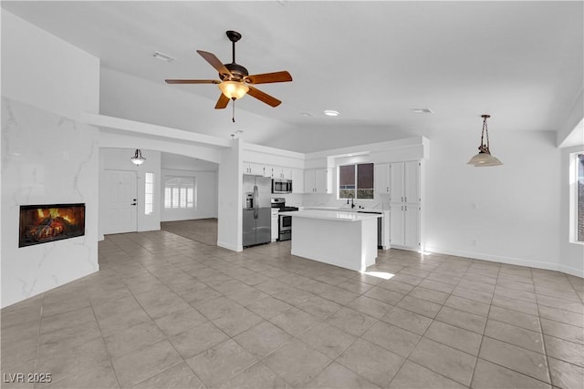 5437 Escallonia St, Las Vegas, NV 89149 - kitchen with stainless steel appliances, open floor plan, vaulted ceiling, light countertops, and white cabinetry