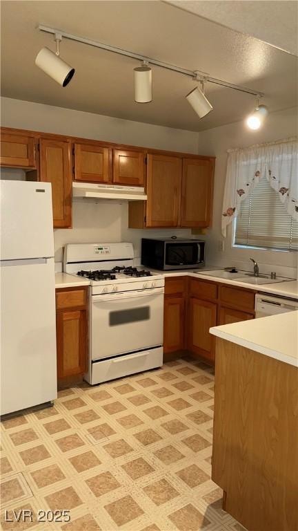 4555 E Sahara Ave Unit 122, Las Vegas, NV 89104 - kitchen featuring white appliances, track lighting, under cabinet range hood, light countertops, and brown cabinetry