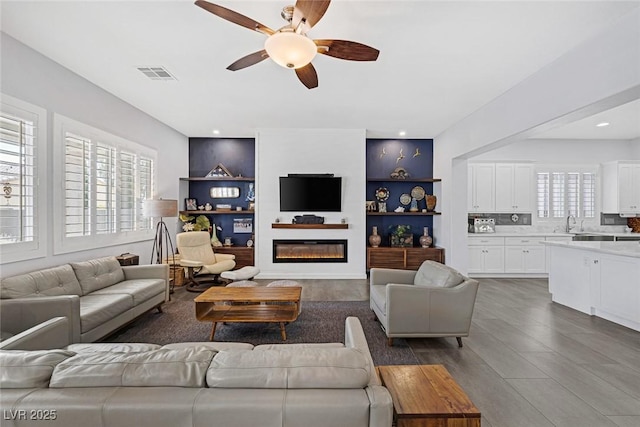 6173 Sabine Ranch Rd, Las Vegas, NV 89131 - living room with ceiling fan, a glass covered fireplace, and dark wood-type flooring