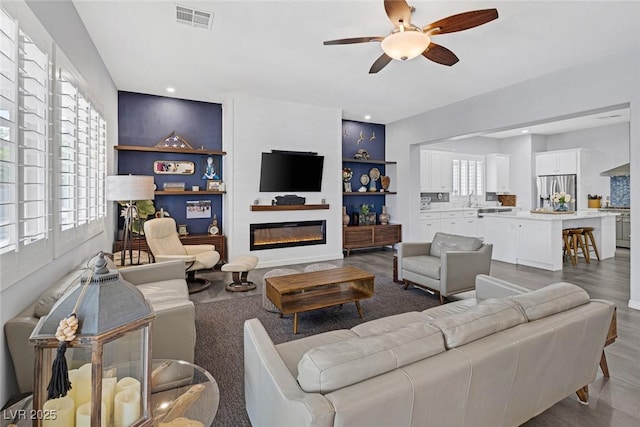 6173 Sabine Ranch Rd, Las Vegas, NV 89131 - living area featuring a ceiling fan, a glass covered fireplace, and wood finished floors