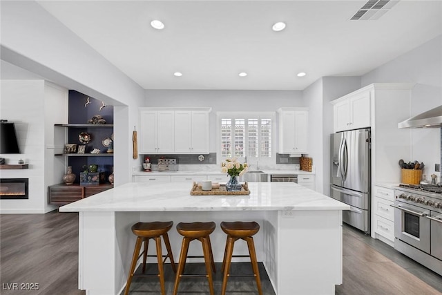 6173 Sabine Ranch Rd, Las Vegas, NV 89131 - kitchen with appliances with stainless steel finishes, a kitchen island, white cabinetry, a kitchen bar, and light stone countertops