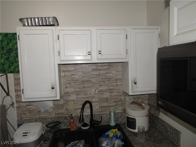 2409 Maroney Ave, Las Vegas, NV 89104 - kitchen featuring white cabinetry, backsplash, and black microwave