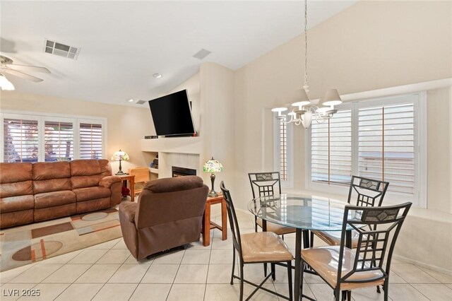 1913 Madagascar Ln, Las Vegas, NV 89117 - dining room featuring a chandelier, light tile patterned floors, a ceiling fan, vaulted ceiling, and a tile fireplace