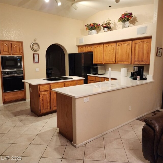 1913 Madagascar Ln, Las Vegas, NV 89117 - kitchen featuring black appliances, a peninsula, light tile patterned flooring, light countertops, and arched walkways