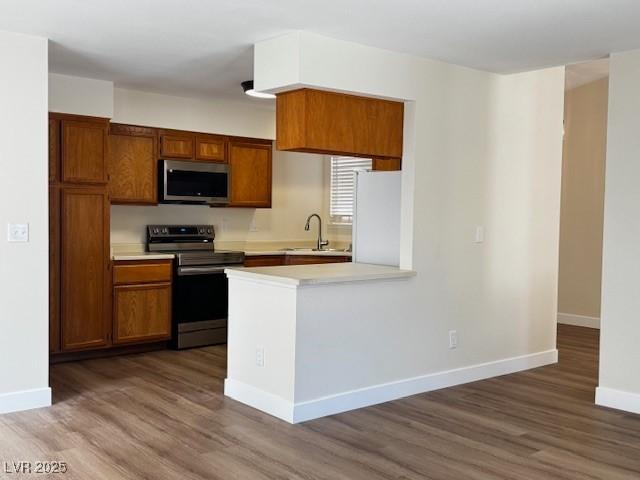 8010 Coffee Tree Ct, Las Vegas, NV 89123 - kitchen with stainless steel appliances, a sink, light countertops, wood finished floors, and brown cabinetry
