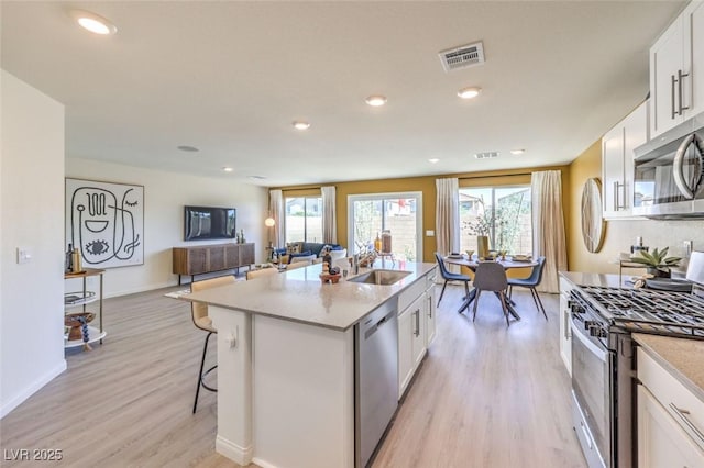 815 Calm Crystal Ct Lot 146, North Las Vegas, NV 89081 - kitchen featuring appliances with stainless steel finishes, a sink, light wood-style flooring, white cabinetry, and a kitchen bar