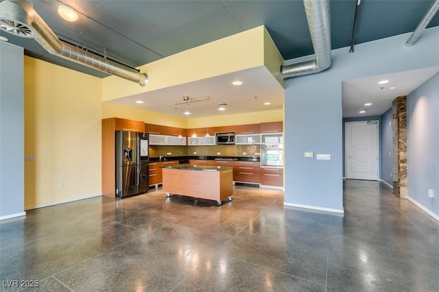 900 Las Vegas Blvd Unit 1209, Las Vegas, NV 89101 - kitchen featuring stainless steel appliances, dark countertops, brown cabinets, a kitchen island, and baseboards
