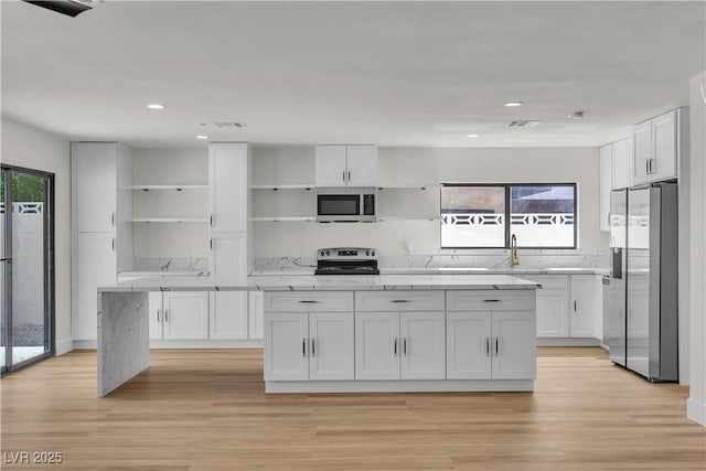 6204 Robin Hood Cir, Las Vegas, NV 89108 - kitchen featuring open shelves, appliances with stainless steel finishes, a sink, white cabinets, and light wood finished floors