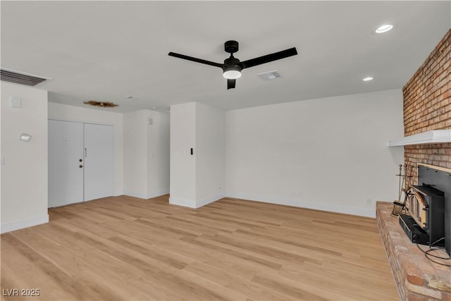 6204 Robin Hood Cir, Las Vegas, NV 89108 - unfurnished living room with ceiling fan, a wood stove, baseboards, light wood finished floors, and recessed lighting