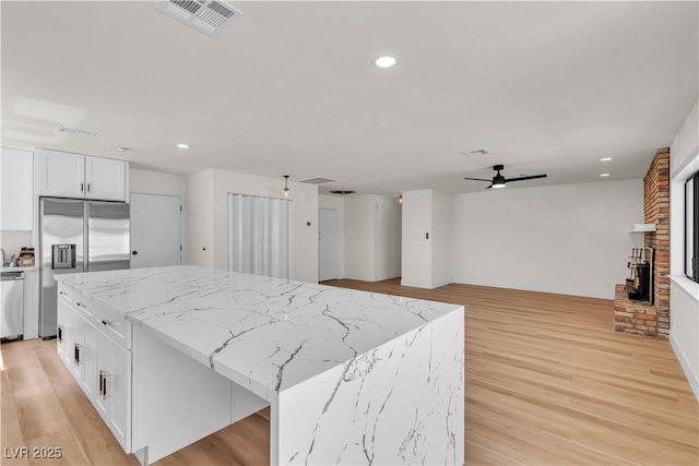 6204 Robin Hood Cir, Las Vegas, NV 89108 - kitchen with stainless steel appliances, a kitchen island, white cabinets, light wood-style floors, and recessed lighting