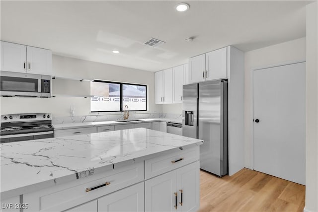 6204 Robin Hood Cir, Las Vegas, NV 89108 - kitchen with stainless steel appliances, a sink, recessed lighting, white cabinetry, and light stone counters