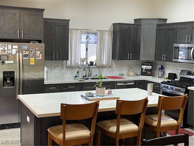 903 Billings St, Henderson, NV 89002 - kitchen with appliances with stainless steel finishes, tasteful backsplash, light countertops, a breakfast bar area, and a center island