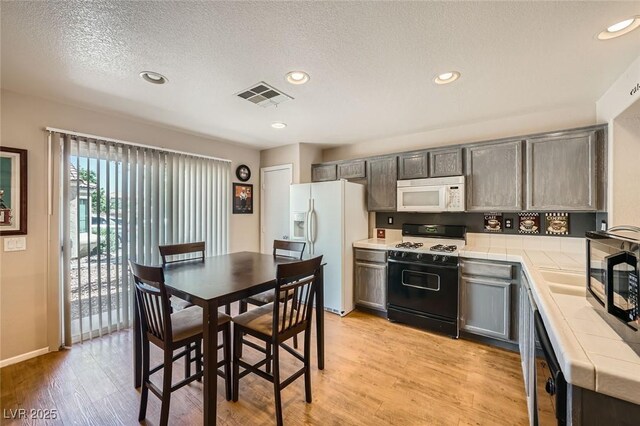 10456 Prairie Schooner Ave, Las Vegas, NV 89129 - kitchen featuring black appliances, tile countertops, light wood-type flooring, a textured ceiling, and recessed lighting