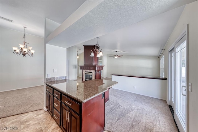 234 Geronimo Ct, Henderson, NV 89074 - kitchen with light colored carpet, a chandelier, a glass covered fireplace, open floor plan, and light stone counters