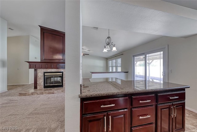 234 Geronimo Ct, Henderson, NV 89074 - kitchen featuring dark brown cabinets, a tile fireplace, light stone countertops, pendant lighting, and a peninsula