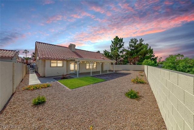 234 Geronimo Ct, Henderson, NV 89074 - back of house at dusk with a tiled roof, a chimney, a fenced backyard, a patio, and stucco siding