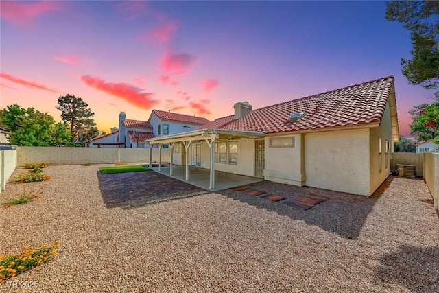 234 Geronimo Ct, Henderson, NV 89074 - back of property at dusk featuring a patio, a chimney, stucco siding, a fenced backyard, and a tiled roof