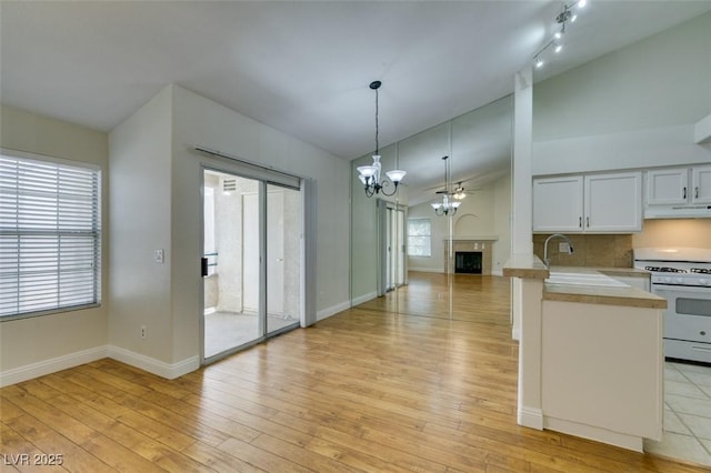 2251 Wigwam Pkwy Unit 824, Henderson, NV 89074 - kitchen with white gas stove, light countertops, under cabinet range hood, open floor plan, and a chandelier