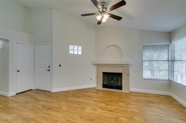 2251 Wigwam Pkwy Unit 824, Henderson, NV 89074 - unfurnished living room with light wood-style flooring, a ceiling fan, a tile fireplace, baseboards, and a towering ceiling