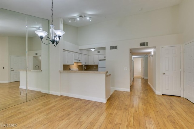 2251 Wigwam Pkwy Unit 824, Henderson, NV 89074 - kitchen featuring a towering ceiling, freestanding refrigerator, a chandelier, a peninsula, and light wood finished floors