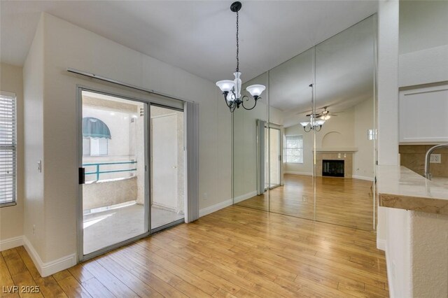 2251 Wigwam Pkwy Unit 824, Henderson, NV 89074 - unfurnished dining area featuring light wood-style flooring, a fireplace, a chandelier, baseboards, and a sink