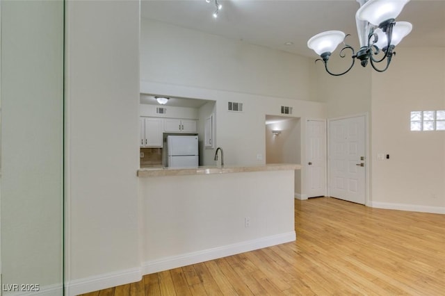 2251 Wigwam Pkwy Unit 824, Henderson, NV 89074 - kitchen with freestanding refrigerator, light countertops, white cabinetry, a towering ceiling, and light wood finished floors