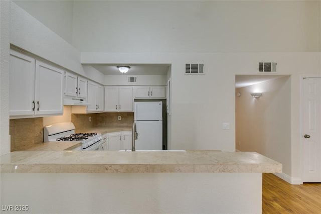 2251 Wigwam Pkwy Unit 824, Henderson, NV 89074 - kitchen with white appliances, backsplash, light wood-style floors, a peninsula, and under cabinet range hood