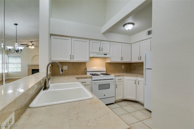2251 Wigwam Pkwy Unit 824, Henderson, NV 89074 - kitchen with white appliances, a sink, under cabinet range hood, tasteful backsplash, and a tiled fireplace