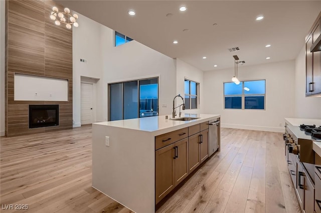 182 Robledo St, Las Vegas, NV 89138 - kitchen with a sink, light wood-style floors, a center island with sink, light countertops, and hanging light fixtures