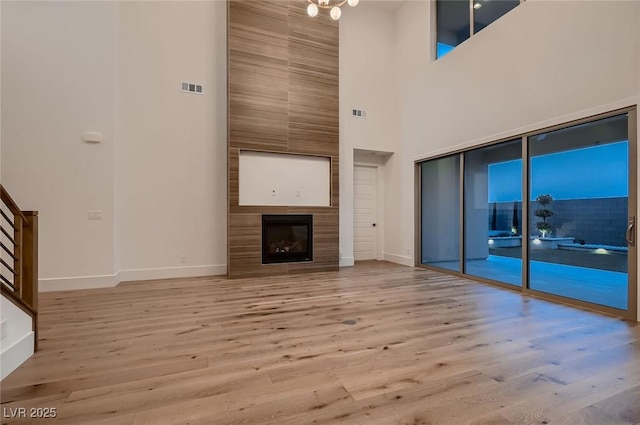 182 Robledo St, Las Vegas, NV 89138 - unfurnished living room featuring a towering ceiling, baseboards, wood finished floors, and a fireplace