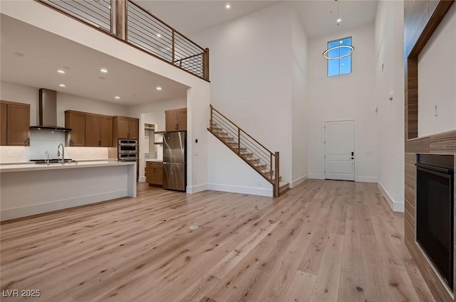182 Robledo St, Las Vegas, NV 89138 - kitchen with appliances with stainless steel finishes, wall chimney range hood, a towering ceiling, a sink, and light countertops