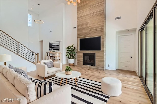 182 Robledo St, Las Vegas, NV 89138 - living area with a high ceiling, stairs, light wood-style floors, a fireplace, and baseboards