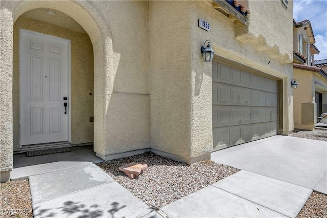 1952 W Hammer Ln, North Las Vegas, NV 89031 - view of exterior entry featuring stucco siding, a tiled roof, and an attached garage