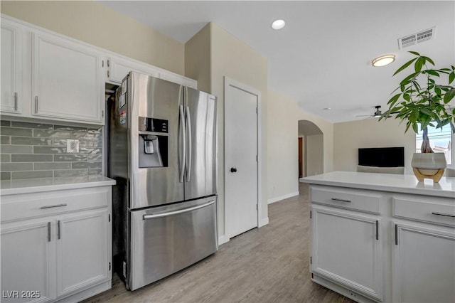 1952 W Hammer Ln, North Las Vegas, NV 89031 - kitchen featuring stainless steel fridge, tasteful backsplash, arched walkways, light countertops, and white cabinetry