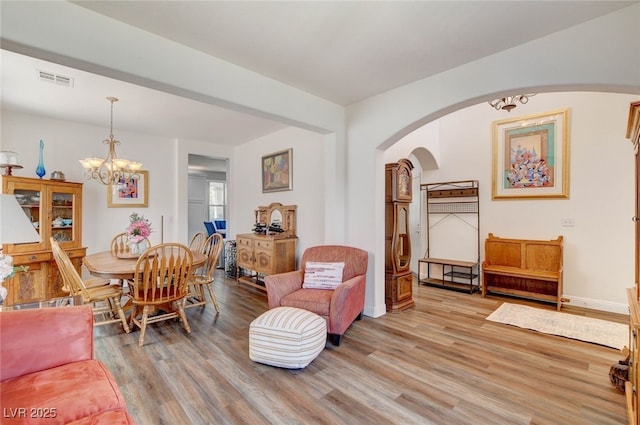831 E Galingale Ct, Henderson, NV 89015 - living room featuring arched walkways, light wood finished floors, a chandelier, and baseboards